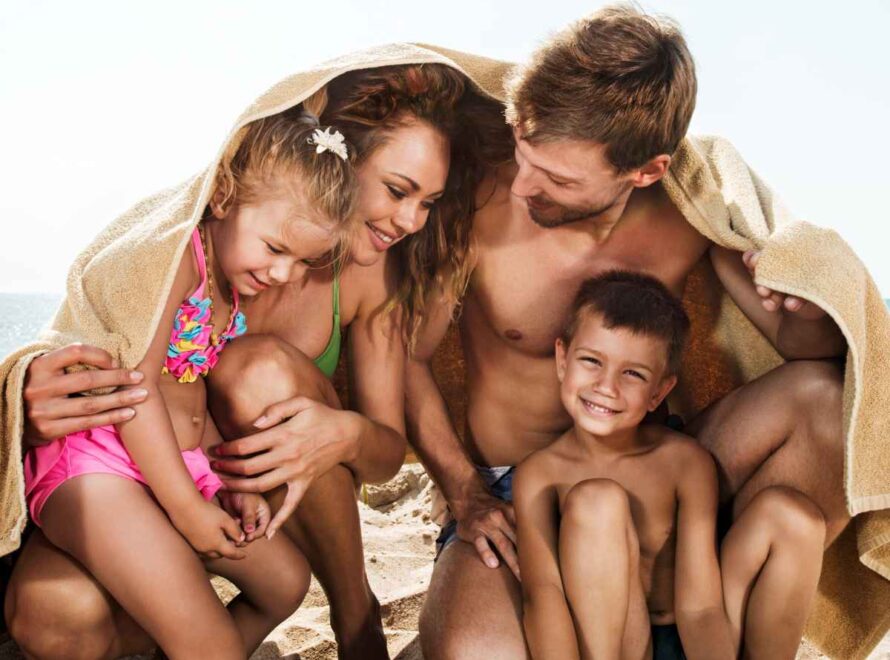 family at the beach with a towel to cover them